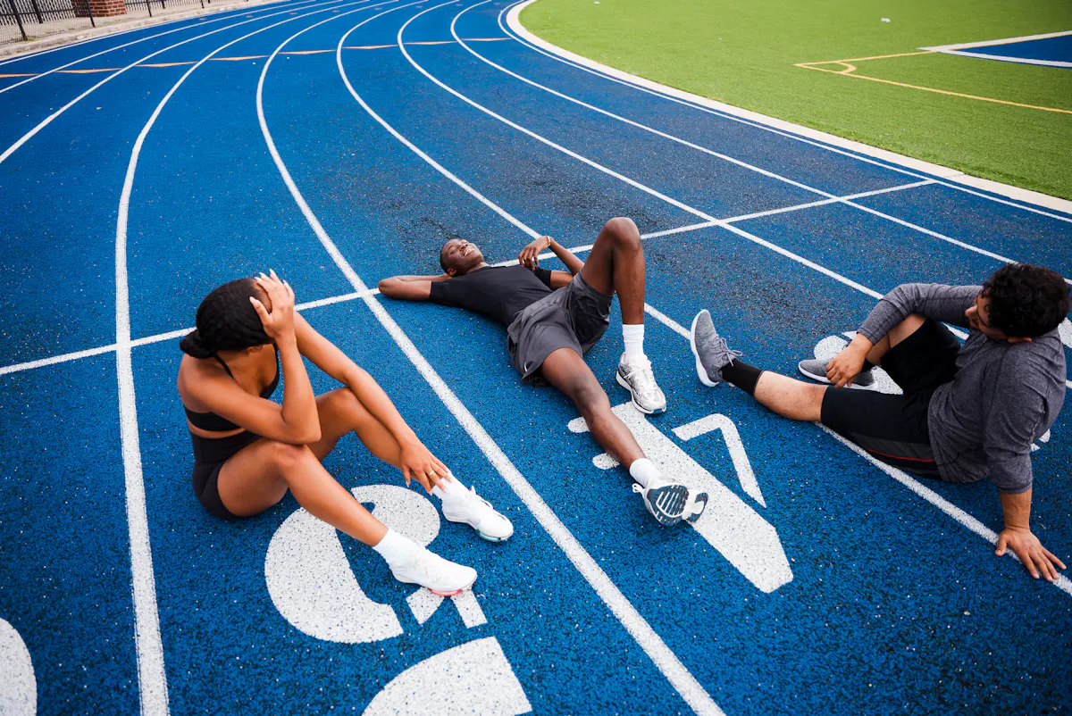 Atletas a descansar numa pista de atletismo depois do treino
